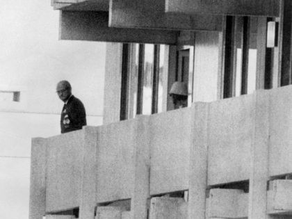 Picture taken on September 5, 1972 shows a Palestinian guerilla member (C) appearing on the balcony of the Israeli house watching an official (L) at the Munich Olympic village.