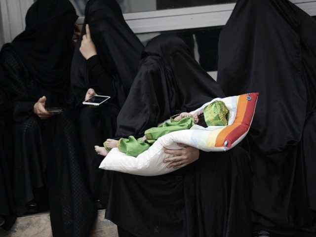 A Bahraini Shiite Muslim woman carries a baby during a ceremony commemorating Ashura, whic