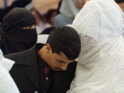 AMMAN, JORDAN - JULY 25: A Groom listens to his veiled bride in a mass wedding July 25, 2003 in Amman, Jordan. One hundred and four brides and grooms made the knot in a mass wedding organized by the Islamic society of (al-Afaf) for philanthropic wedding, celebrating with their families …