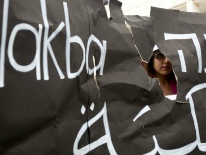 An Israeli Arab student is seen through a torn placard during a ceremony commemorating the 'Nakba Day' in front of Tel Aviv university on May 14, 2012 which was organised by Arab Israelis and left-wing students.