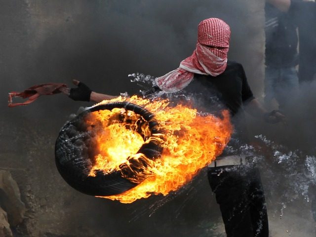 A Palestinian sets fire to a tyre during clashes between hundreds of Palestinians and Isra