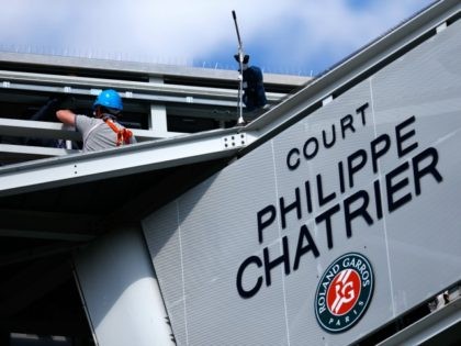 People work on the scoreboard above Court Philippe Chatrier after a piece of metal was blown off in high winds during the men's singles quarterfinal match between Kei Nishikori of Japan and Jo-Wilfried Tsonga of France on day of the 2015 French Open at Roland Garros on June 2, 2015 …