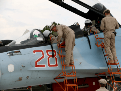 Russian servicemen assist air force pilots in a Russian Sukhoi Su-30SM fighter jet before