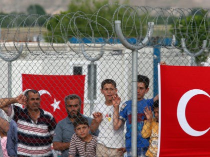 Migrants stand behind a fence at the Nizip refugee camp in Gaziantep province, southeastern Turkey, Saturday, April 23, 2016. German Chancellor Angela Merkel and top European Union officials, under pressure to reassess a migrant deportation deal with Turkey, are traveling close to Turkey's border with Syria on Saturday in a …
