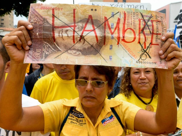 A woman holds a sign reading 'Hunger' during a demo against the government of Venezuelan President Nicolas Maduro in Caracas on May 14, 2016. Venezuela braced for protests Saturday after Maduro declared a state of emergency to combat the 'foreign aggression' he blamed for an economic crisis that has pushed the country to the brink of collapse. / AFP / FEDERICO PARRA (Photo credit should read FEDERICO PARRA/AFP/Getty Images)