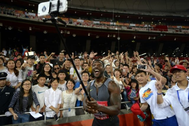 Justin Gatlin of the US (C) uses a mobile phone to take a picture with fans as he celebrat