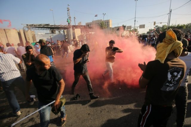 Supporters of Iraqi cleric Moqtada al-Sadr flee the smoke grenades fired by security force