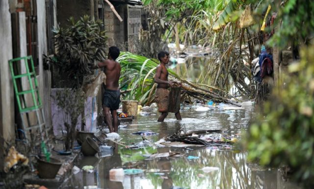 Sri Lankan residents clear debris from outside homes following flooding in the Kolonnawa s