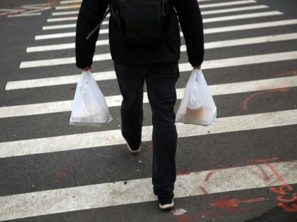 A man walks out of a store with plastic bags on May 5, 2016 in New York