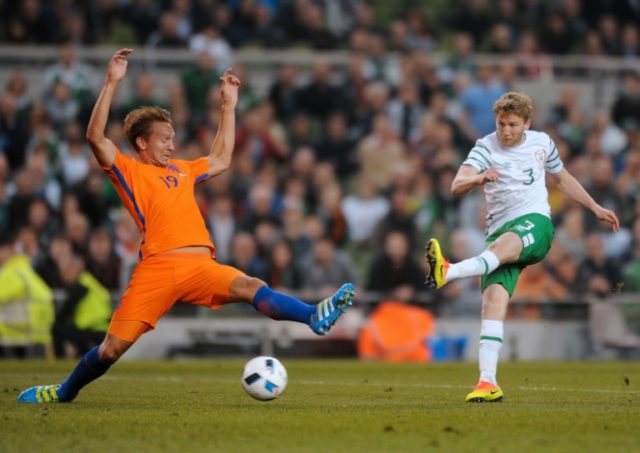 Ireland's Eunan O'Kane (R) takes a shot as Netherlands striker Luuk de Jong challenges dur