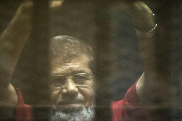 Egypt's ousted Islamist president Mohamed Morsi stands behind bars during his trial at the