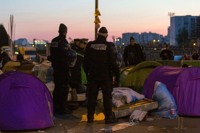 French police officers and gendarmes evacuate migrants from a makeshift camp under the Sta