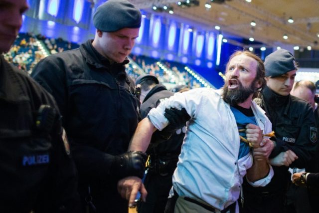 Policemen escort an environmental activist from the hall after he demonstrated during the