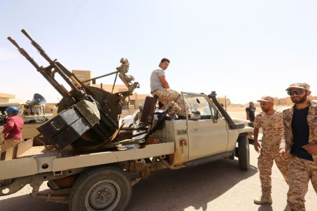 Libyan pro-government forces walk next to their vehicle mounted with a machine gun on May