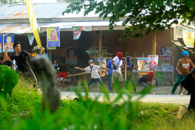 Supporters of a local candidate throw stones at supporters of a rival candidate during a c