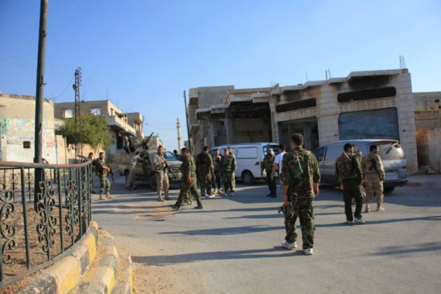 Syrian government forces walk on a street after they took control of the Syrian village of