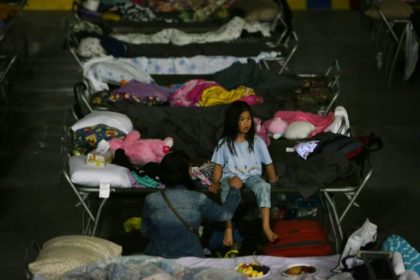 A young girl sits on a cot at a makeshift evacuee center in Lac la Biche, Alberta after f