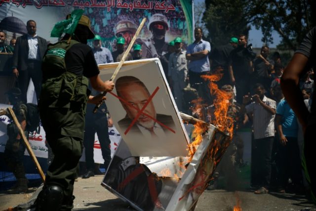 Palestinian supporters of the Islamist Hamas movement burn placards bearing pictures of Av