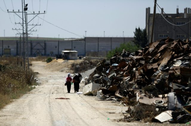 Palestinian women walk past areas where Hamas militants were located near the border with