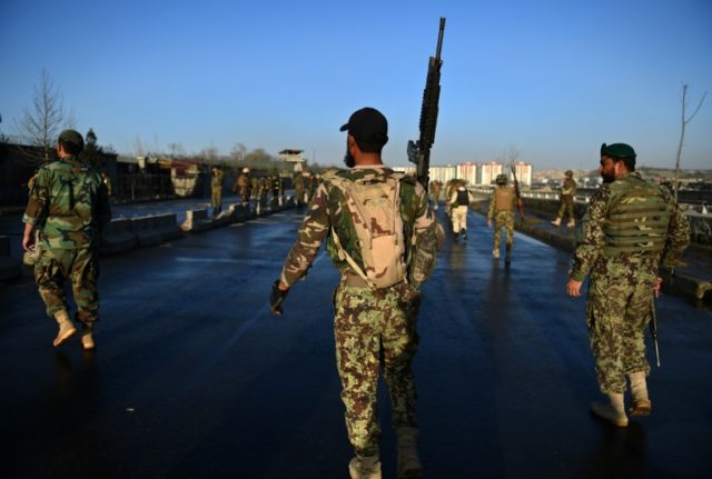 Afghan security personnel gather near the scene of a suicide bombing in February