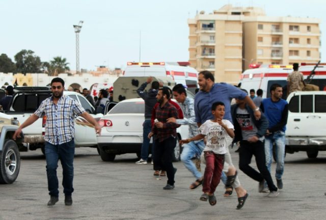 Libyan demonstrators run for cover from shelling during a protest in Benghazi calling for