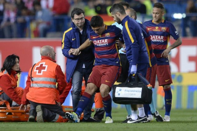 Barcelona forward Luis Suarez (centre) is helped by medical staff after being injured duri