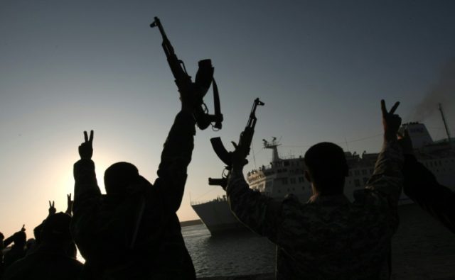 Rebel fighters hold their weapons aloft to welcome a Turkish ship arriving from Misrata to