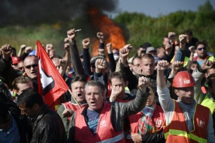 Striking workers are evacuated by French riot police as they block the access to an oil de