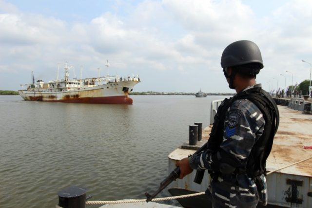 An Indonesian Navy officer in April, standing before a Chinese trawler that was allegedly