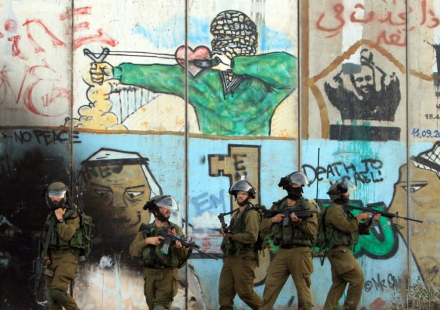 Israeli soldiers stand in front of the graffiti-covered controversial separation barrier d