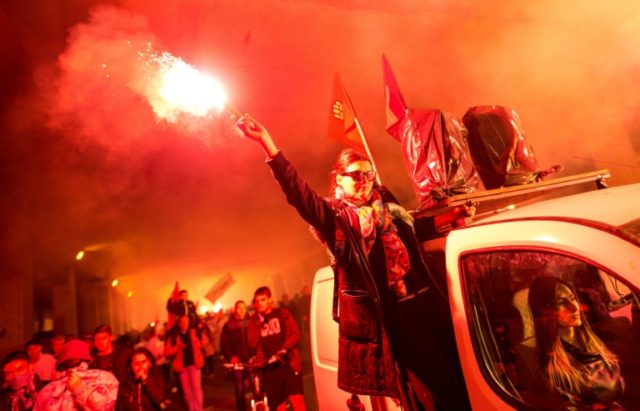 Protestors light flares and wave flags during an anti-government rally in Skopje on May 16