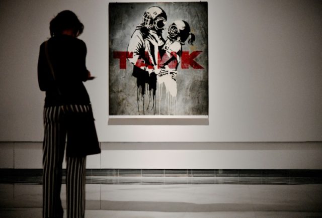 A woman looks at a paiting entitled "Think tank" by England-based graffiti artist Banksy d