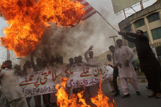 A Pakistani demonstrator holds a burning US flag during a protest in Multan on May 24, 201