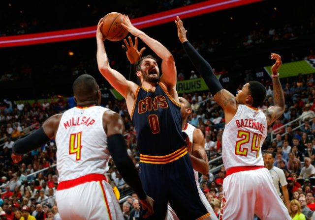 Kevin Love (C) of the Cleveland Cavaliers drives the basket against Paul Millsap (L) and K