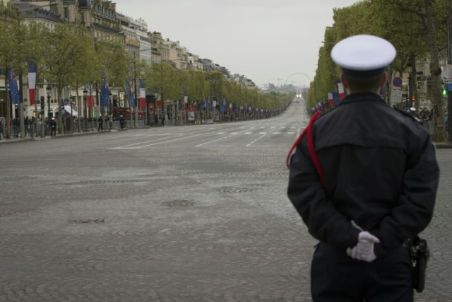 A French policeman stands guard at the top of the empty Champs-Elysees in Paris on April 2