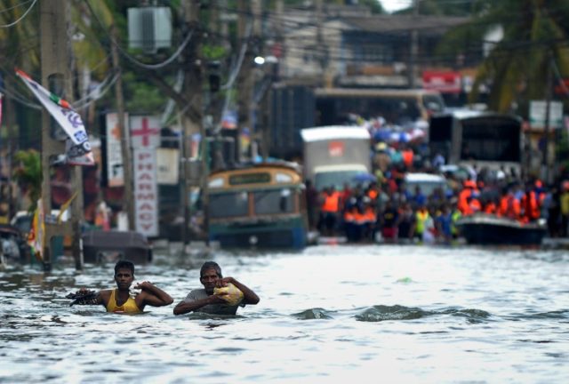 Sri Lankans wade through floodwaters in the Kolonnawa suburb of Colombo on May 20, 2016, f