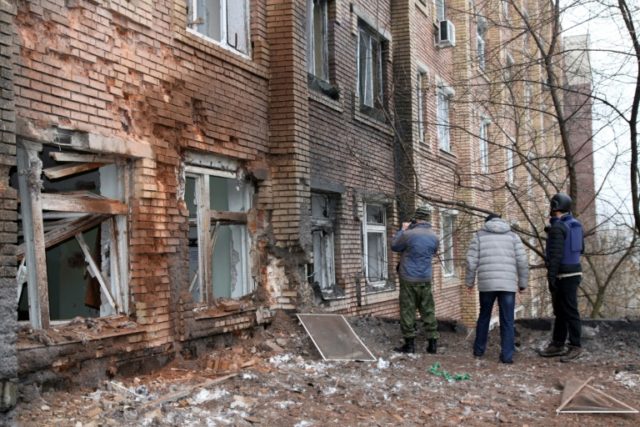 Journalists stand in front of a hospital destroyed after shelling between Ukrainian forces