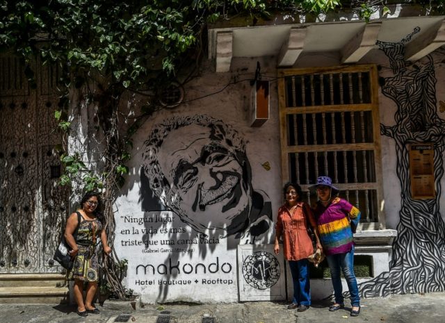 Tourists pose for a snapshot in front of a mural painting depicting the late Colombian wri