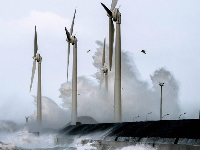 Waves break against the Boulogne-sur-mer harbour pier where wind turbines stand on Februar