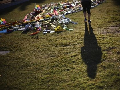 A woman casts a shadow while visiting a makeshift memorial downtown to the victims of the Pulse nightclub mass shooting Thursday, June 16, 2016, in Orlando, Fla. (AP Photo/David Goldman)