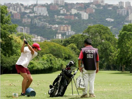 A member of the Country Club plays golf as his caddy stands by in Caracas, Venezuela, Tues