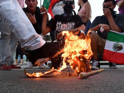 A Trump hat burns during a protest near where Republican presidential candidate Donald Tru