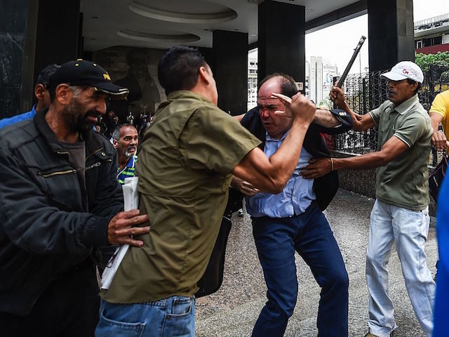 TOPSHOT - Supporters of Venezuelan president Nicolas Maduro hit opposition deputy Julio Borges(C), during a demonstration in front of the National Electoral Council in Caracas on June 9, 2016. / AFP / JUAN BARRETO (Photo credit should read JUAN BARRETO/AFP/Getty Images)
