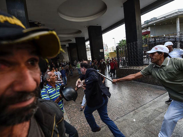 Supporters of Venezuelan president Nicolas Maduro hit opposition deputy Julio Borges(C), during a demonstration in front of the National Electoral Council in Caracas on June 9, 2016. / AFP / JUAN BARRETO (Photo credit should read JUAN BARRETO/AFP/Getty Images)