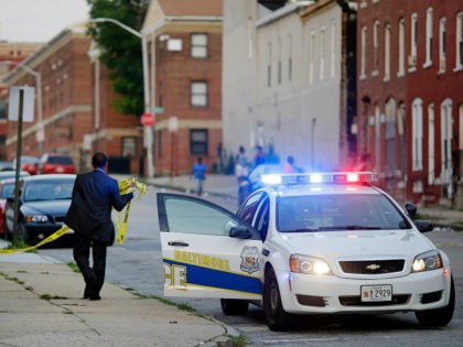 In this July 30, 2015 picture, a member of the Baltimore Police Department removes crime scene tape from a corner where a victim of a shooting was discovered in Baltimore. Murders are spiking again in Baltimore, three months after Freddie Gray’s death in police custody sparked riots. This year’s monthly …