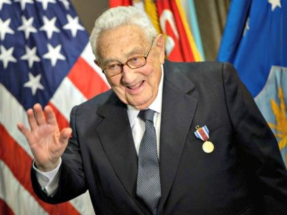 Former US Secretary of State Henry Kissinger waves after receiving an award during a cerem