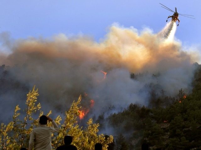 People watch a firefighting plane dropping water at Pendeli mountain in Dionissos in a sub