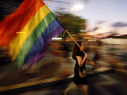 An Israeli woman waves a rainbow flag as she takes part in a demonstration of solidarity with the victims of an attack on a gay centre, in Tel Aviv's Rabin Square on August 8, 2009.
