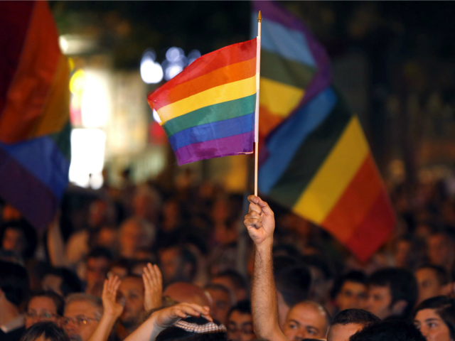A man waves a rainbow flag as thousands of Israelis from the gay community and supporters gather in downtown Jerusalem on August 1, 2015 to protest against discrimination and violence against the gay community following an attack at the Jerusalem Gay Pride parade.
