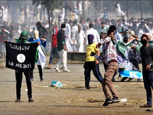 SRINAGAR, INDIA - SEPTEMBER 25: Kashmiri Muslim protesters throw stone as they carry a ISIS flag and portraits of local militants as tear gas shells exploded near them during the clashes between protesters and security men on September 25, 2015, in Srinagar, India. Kashmir valley witnessed restrictions with the government …